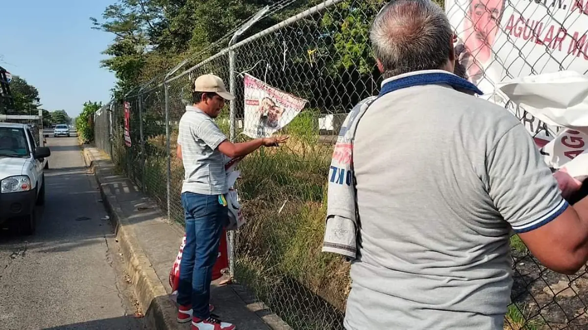 personas quitando propaganda politica